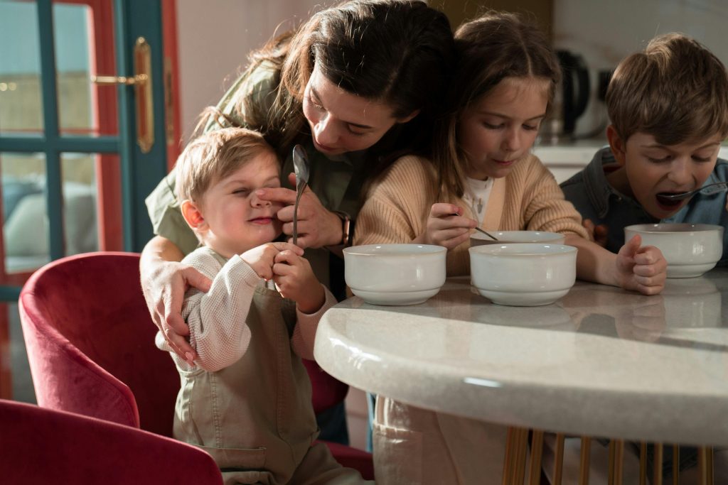 Mama siedzi przy stole z dziećmi.