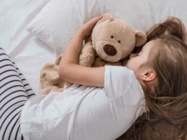 Śliczna mała dziewczynka w łóżku z miękką zabawką