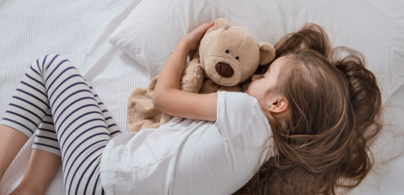 Śliczna mała dziewczynka w łóżku z miękką zabawką